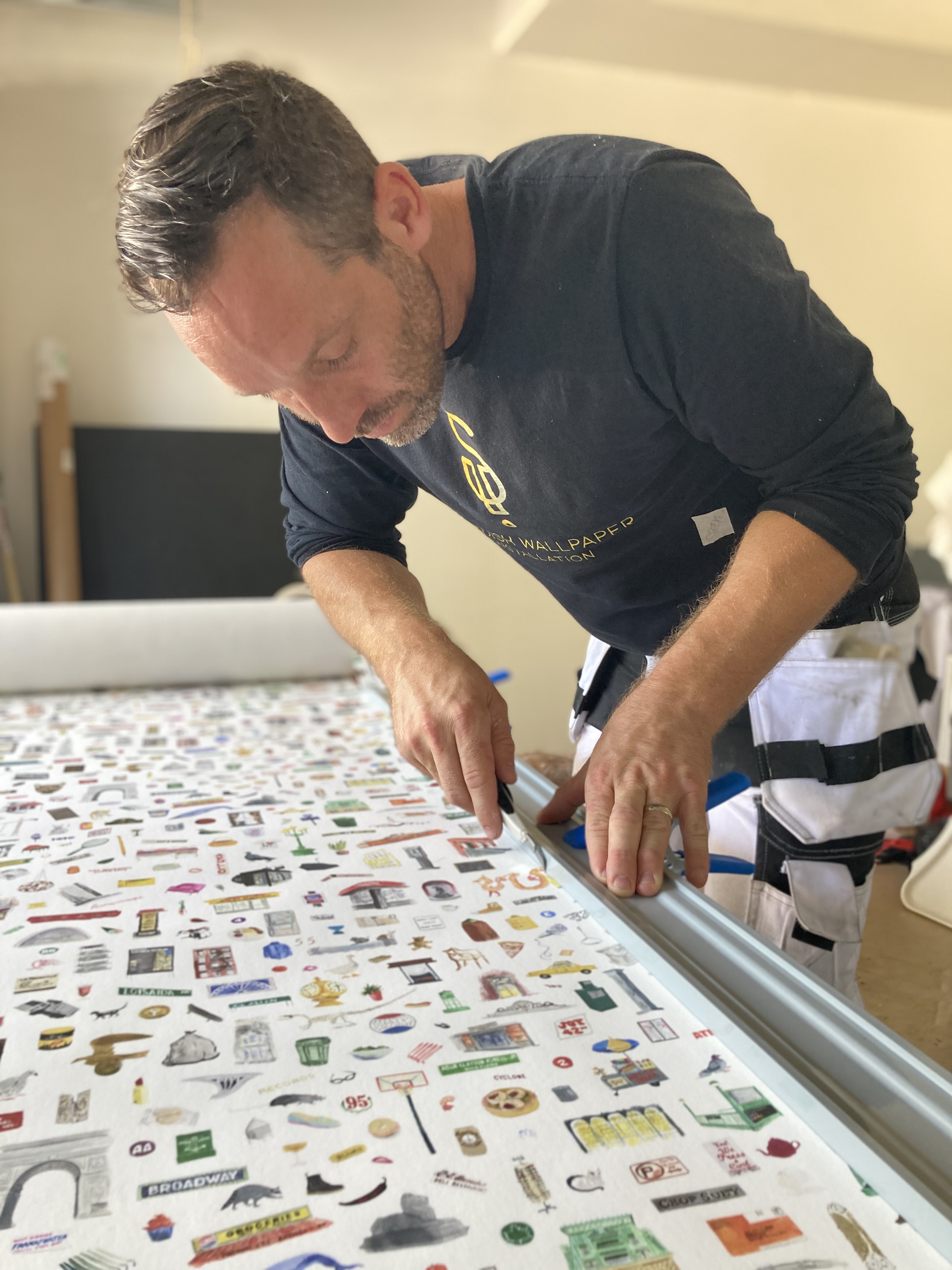 Wallpaper hanger trimming wallpaper.